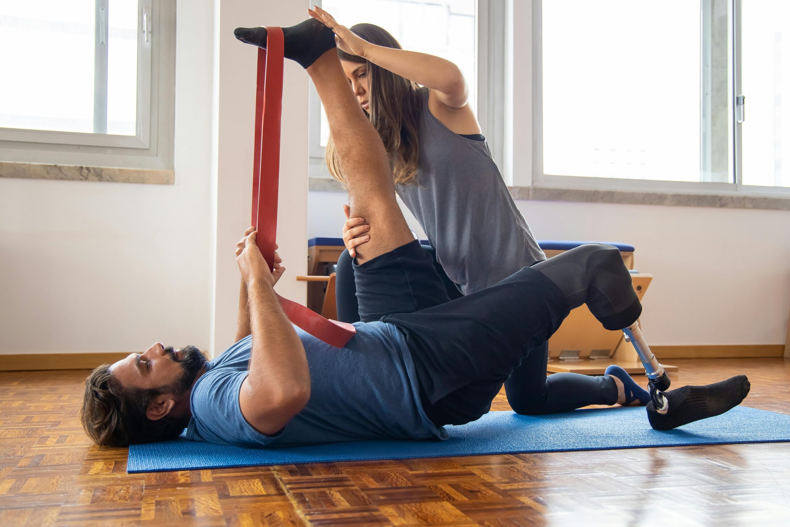 Man in rehabilitation exercises with a trainer, focusing on prosthetic leg recovery.