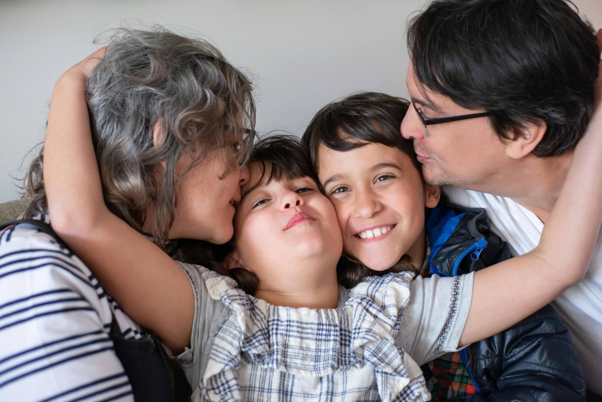 A joyful family of four sharing a warm embrace, highlighting love and togetherness indoors.